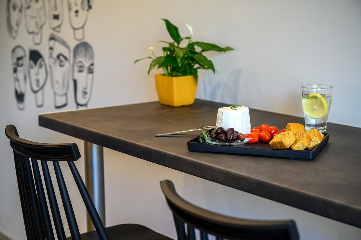 Close-up of a meal setup in the shared kitchen at Psiri Vibes Hotel, featuring cheese, olives, and bread.